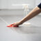 a-person-wiping-a-tiled-floor-with-a-red-cloth-beside-a-spray-bottle.